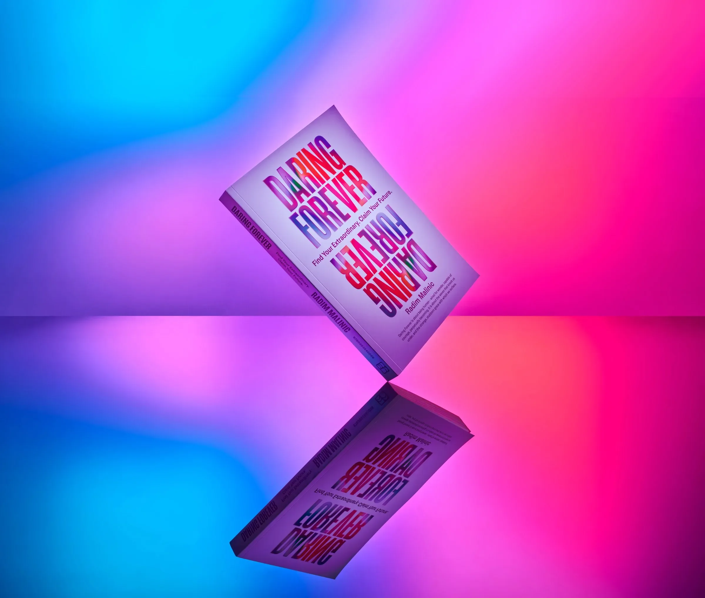 Daring Forever paperback balanced on a mirrored surface against a blue and pink gradient, Daring Forever book by Radim Malinic