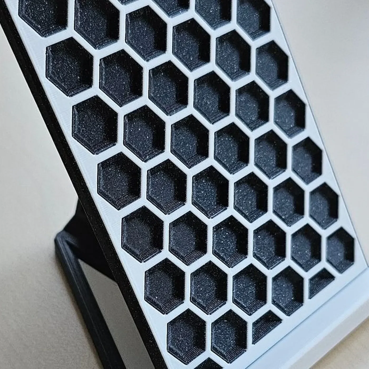 3D printed stand with hexagon pattern holding phone on desk