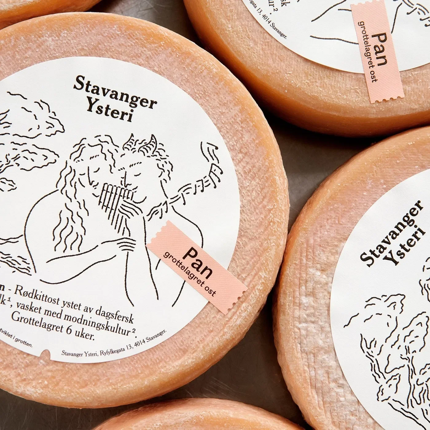 Tactile macro detail of round cheese labels showcasing circular embossing, Stavanger Ysteri wordmark, and pink debossed sticker tag in packaging design