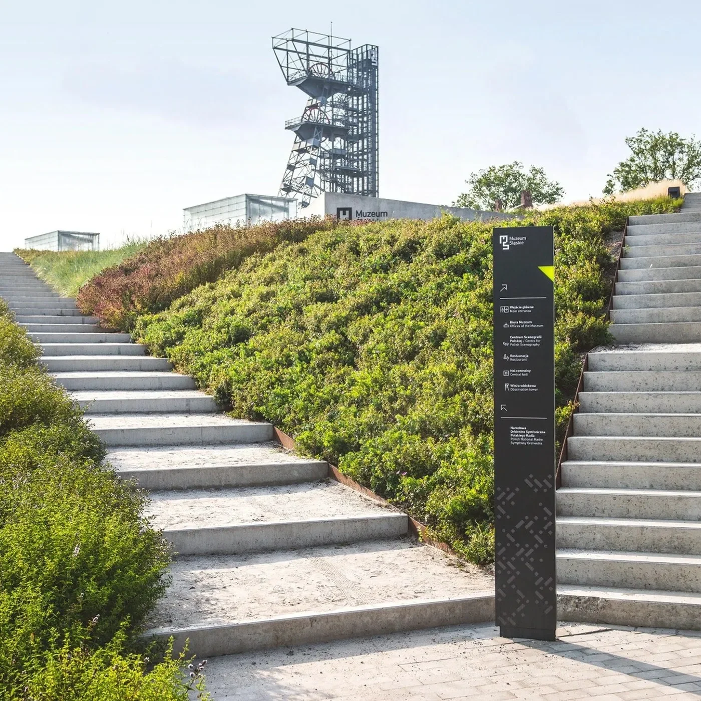 Matte anthracite directional totem standing between concrete stairways showcasing spatial design at the Silesian Museum
