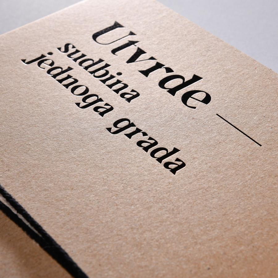 Macro of the high-contrast serif title pressed into the kraft cover, binding cord at the frame edge.
