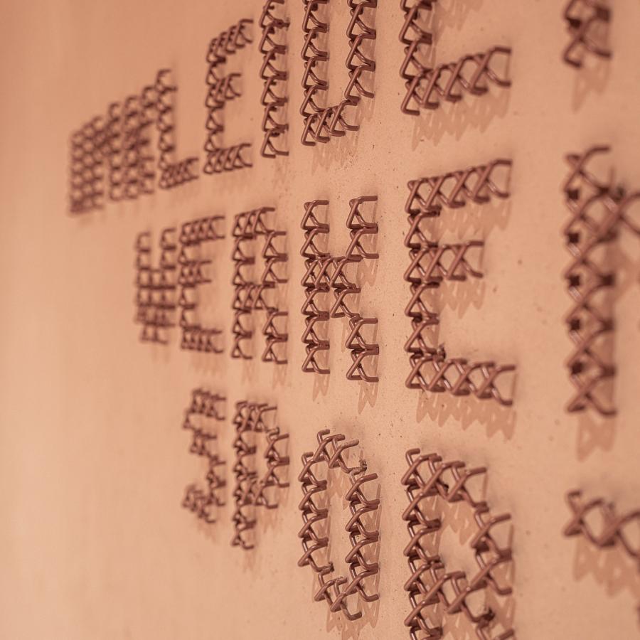 Copper cross-stitch wayfinding lettering in macro at Education Center Kössen