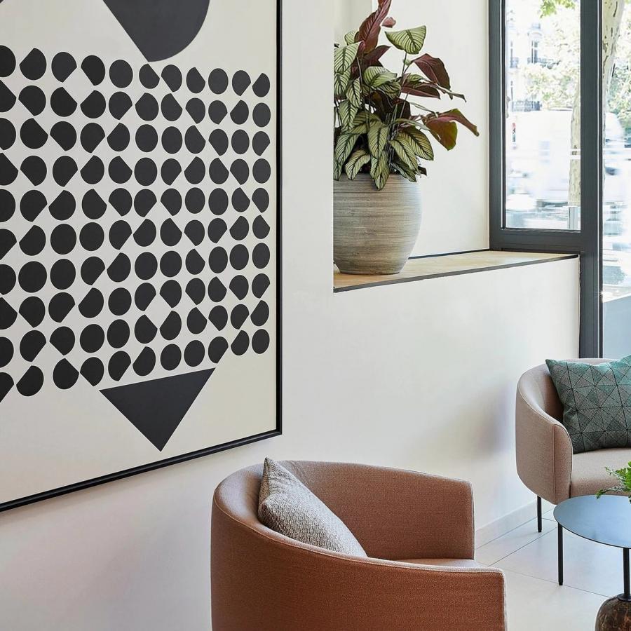 Framed Victor Vasarely inspired op-art geometric artwork installed above green velvet banquette seating at Crowne Plaza Paris République by Marçal Prats