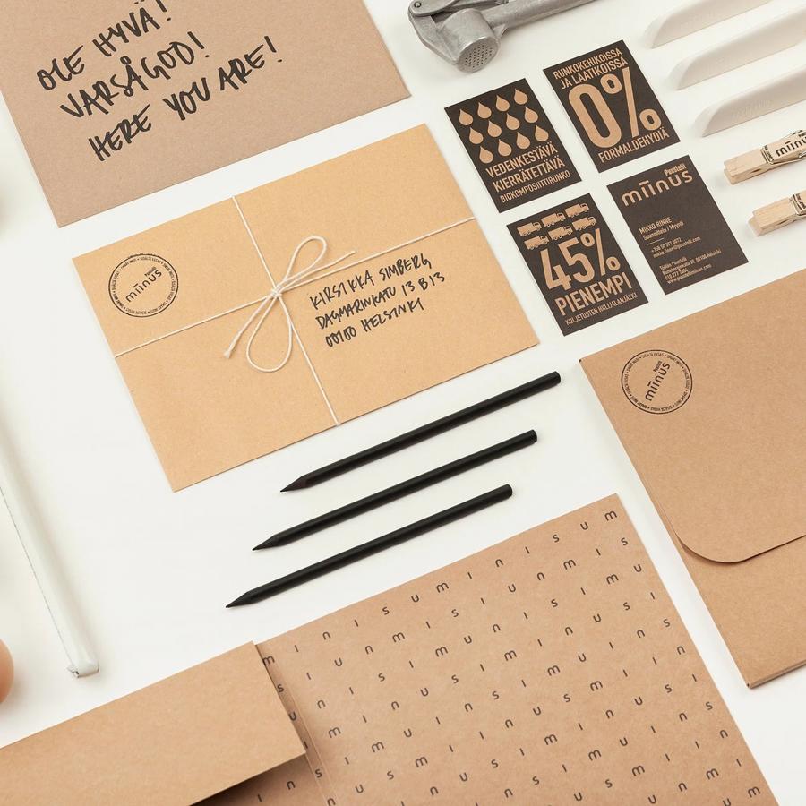 Puustelli Miinus brand identity stationery flat lay with kraft envelopes, charcoal infographic cards, and biocomposite knives by BOND Creative Agency