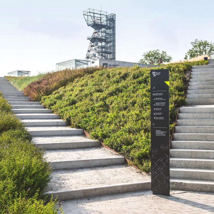 Matte anthracite directional totem standing between concrete stairways showcasing spatial design at the Silesian Museum